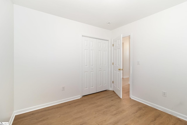 unfurnished bedroom featuring baseboards, a closet, and light wood finished floors