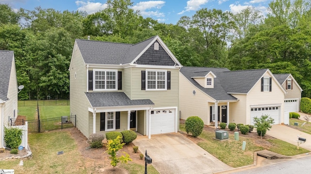 traditional-style home with a shingled roof, a front lawn, fence, and driveway