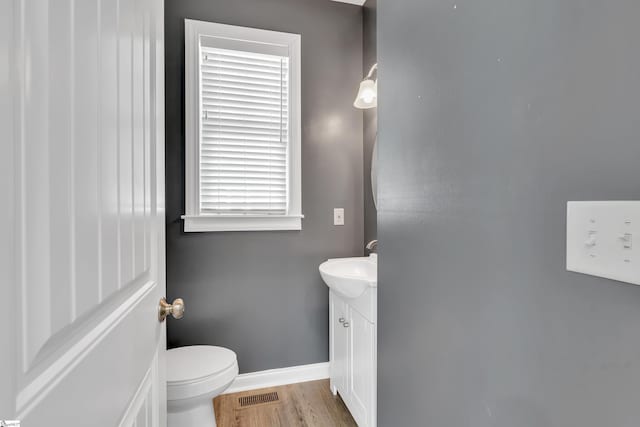 bathroom featuring visible vents, wood finished floors, vanity, baseboards, and toilet