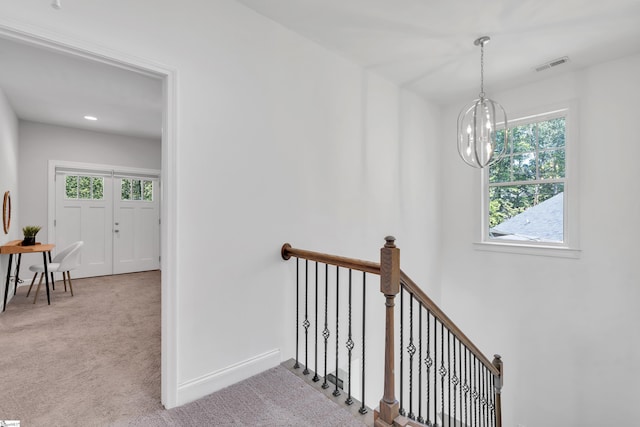 stairs featuring visible vents, carpet, a wealth of natural light, and an inviting chandelier