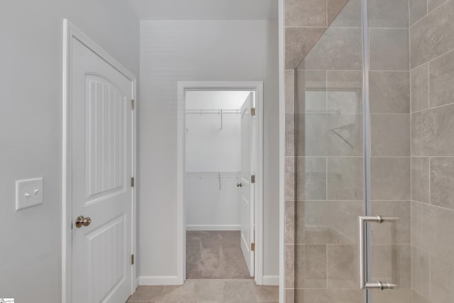 bathroom with baseboards, a shower stall, and a spacious closet