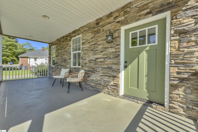 view of exterior entry featuring covered porch and stone siding