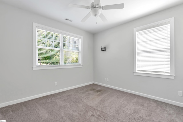 carpeted spare room with a ceiling fan, baseboards, and visible vents