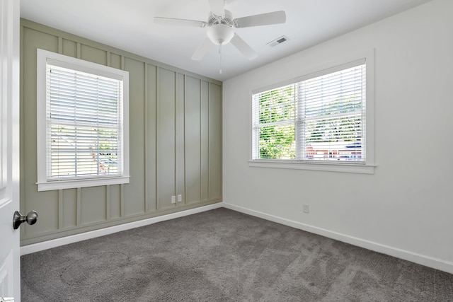 empty room with visible vents, a ceiling fan, a decorative wall, baseboards, and carpet flooring