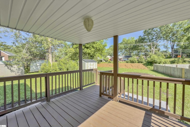 wooden terrace with an outdoor structure, a fenced backyard, a lawn, and a storage shed