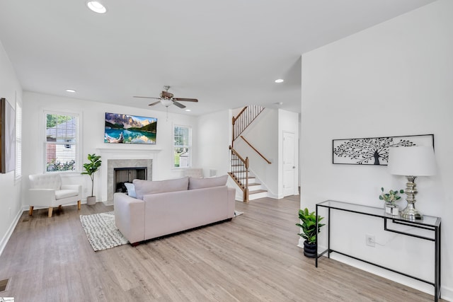 living room featuring a healthy amount of sunlight, baseboards, a fireplace, and light wood-style flooring