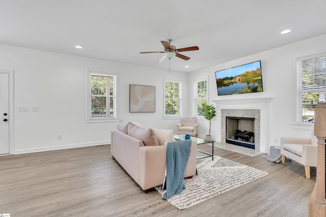 living area with plenty of natural light, ceiling fan, light wood-type flooring, and a premium fireplace