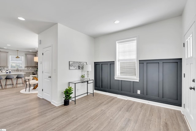entrance foyer featuring recessed lighting, wainscoting, light wood finished floors, and a decorative wall
