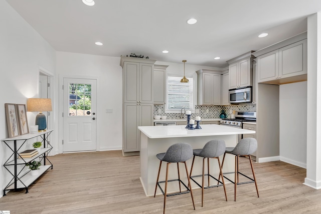 kitchen with plenty of natural light, gray cabinets, appliances with stainless steel finishes, and a breakfast bar