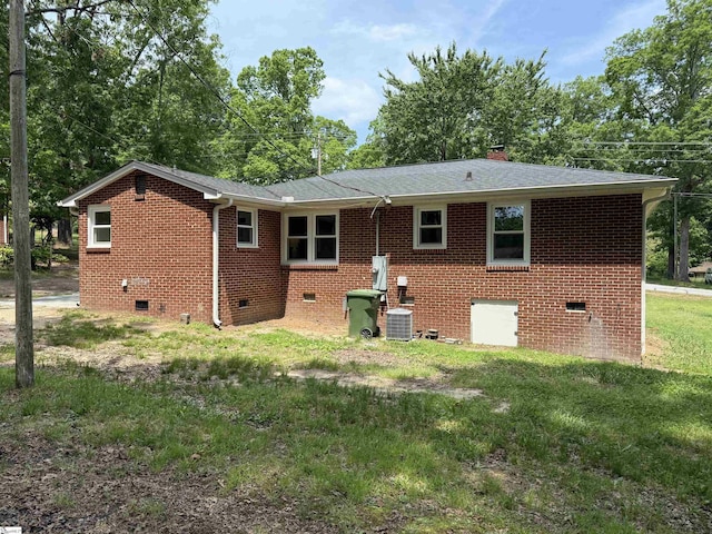 back of property with a chimney, brick siding, a shingled roof, crawl space, and central air condition unit