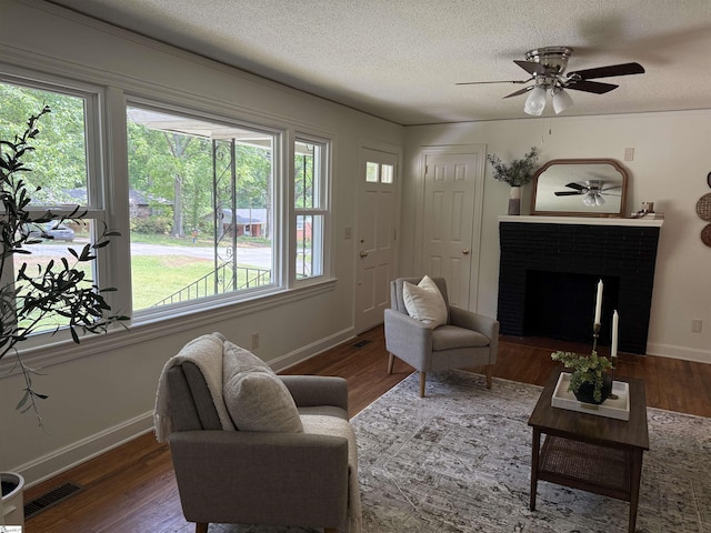 living area with visible vents, baseboards, wood finished floors, and a healthy amount of sunlight