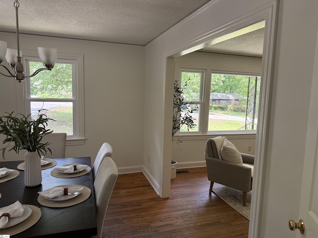 dining space featuring an inviting chandelier, baseboards, a textured ceiling, and dark wood-type flooring