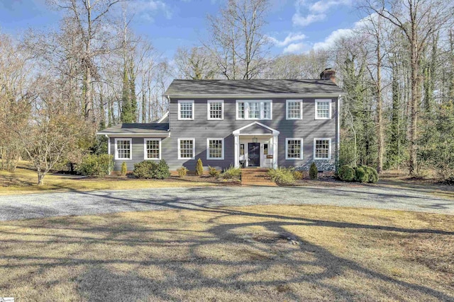 colonial house featuring a front yard and a chimney