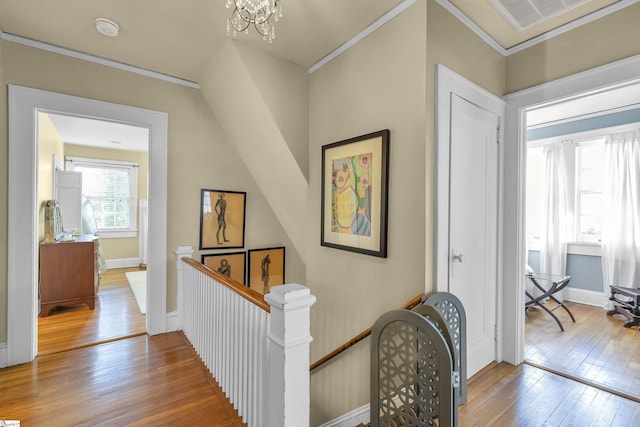 hallway with crown molding, hardwood / wood-style flooring, and an upstairs landing