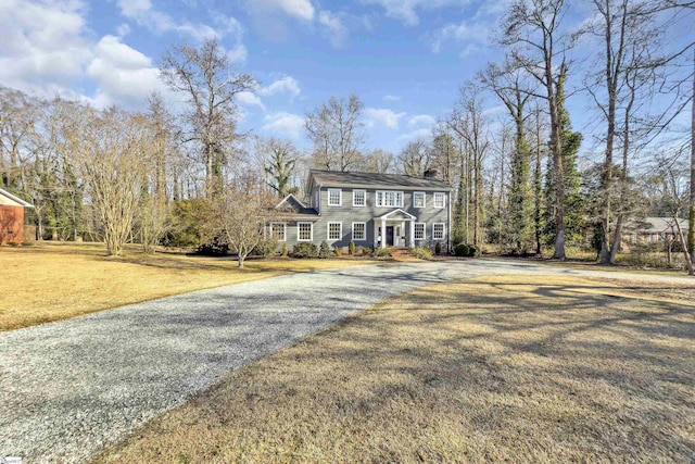 colonial home with a chimney, a front lawn, and aphalt driveway