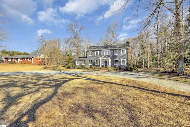 colonial home featuring a front lawn and a chimney