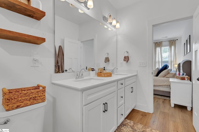 full bath featuring a sink, ensuite bathroom, double vanity, and wood finished floors