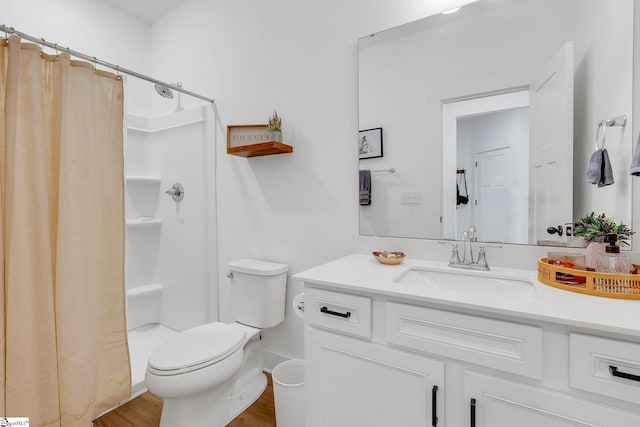 bathroom featuring wood finished floors, toilet, a shower with shower curtain, and vanity