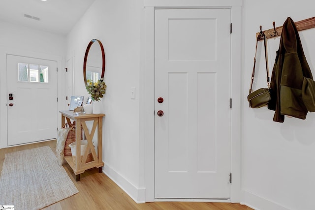 foyer with baseboards, light wood-type flooring, and visible vents