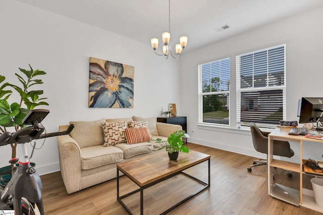 living area with an inviting chandelier, baseboards, wood finished floors, and visible vents