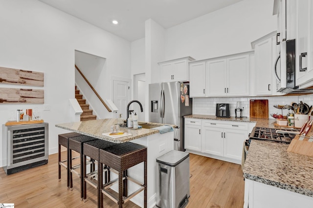 kitchen with light wood-style floors, a sink, wine cooler, and stainless steel appliances