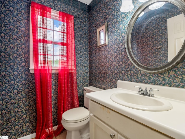 bathroom with vanity, toilet, and wallpapered walls
