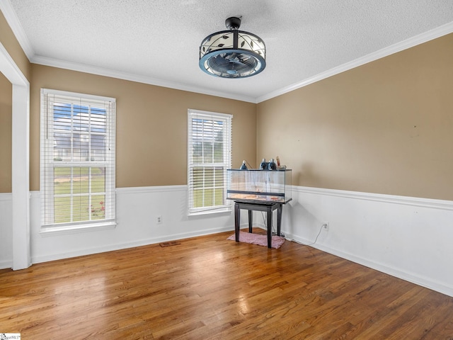interior space with crown molding, a textured ceiling, and wood finished floors
