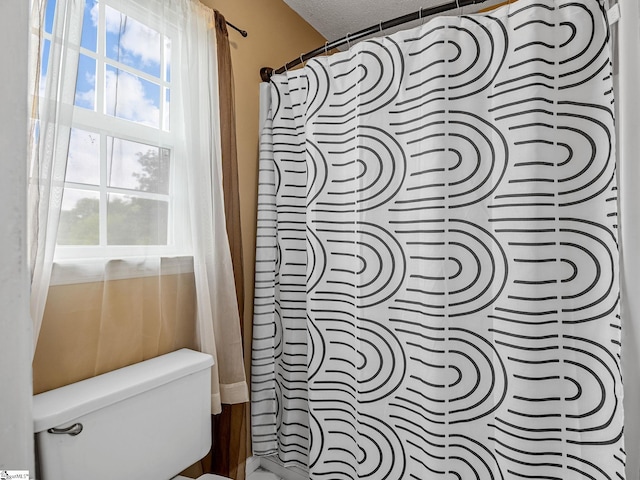 full bathroom with curtained shower, a healthy amount of sunlight, and toilet