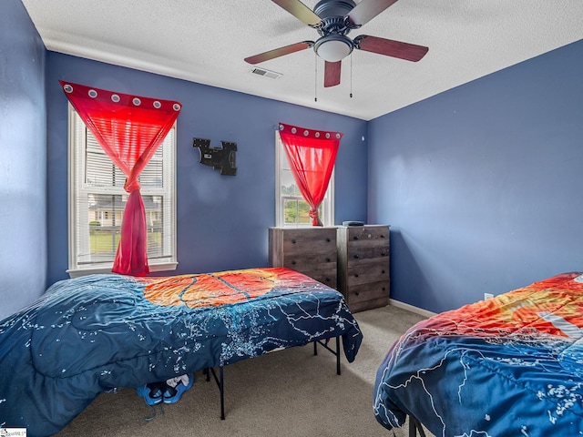 carpeted bedroom featuring a textured ceiling, visible vents, and ceiling fan