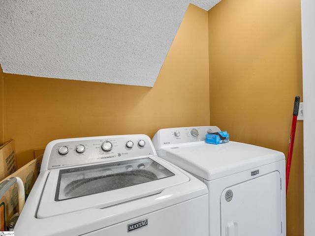 washroom with a textured ceiling and washer and dryer