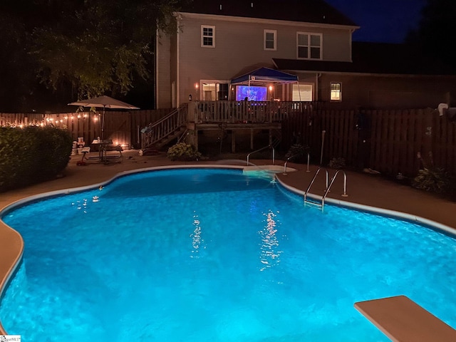 pool at twilight with a fenced in pool, fence, and a wooden deck