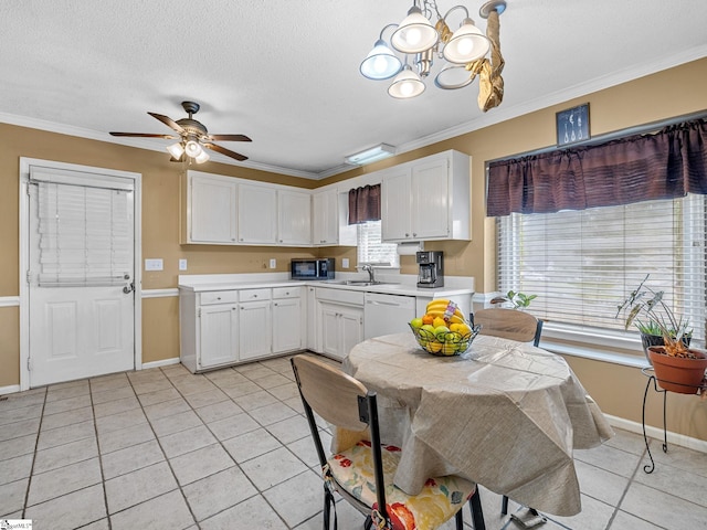 kitchen with crown molding, a sink, light countertops, baseboards, and light tile patterned floors