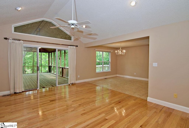 spare room with a textured ceiling, vaulted ceiling, wood finished floors, baseboards, and ceiling fan with notable chandelier