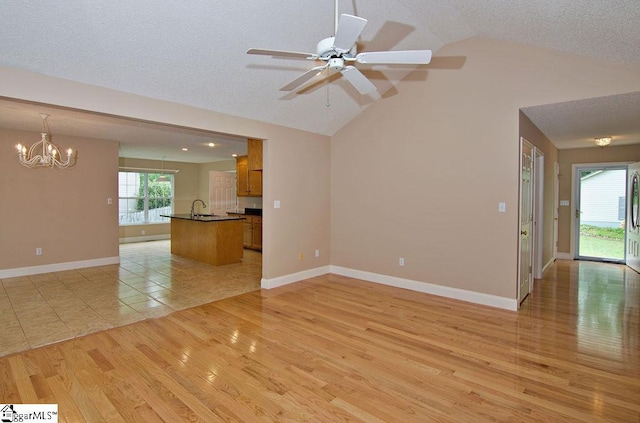 unfurnished living room featuring a textured ceiling, baseboards, ceiling fan with notable chandelier, light wood finished floors, and lofted ceiling