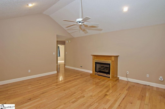 unfurnished living room with a fireplace with raised hearth, a ceiling fan, baseboards, light wood-type flooring, and vaulted ceiling