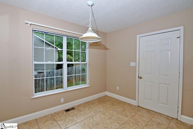 unfurnished dining area with visible vents, a textured ceiling, baseboards, and light tile patterned flooring