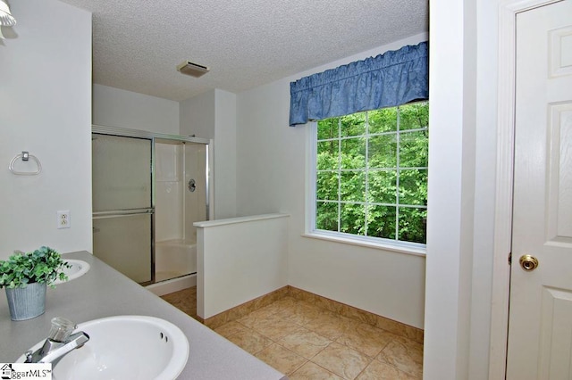 full bath with baseboards, a textured ceiling, tile patterned floors, a shower stall, and a sink
