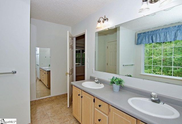 full bath featuring a sink, a textured ceiling, tile patterned flooring, and double vanity
