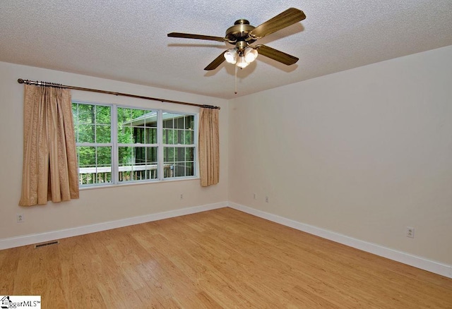 spare room featuring baseboards, a textured ceiling, light wood-style flooring, and a ceiling fan