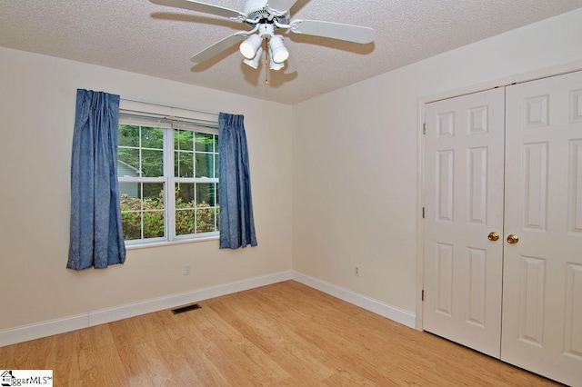 unfurnished room with ceiling fan, a textured ceiling, visible vents, baseboards, and light wood-style floors