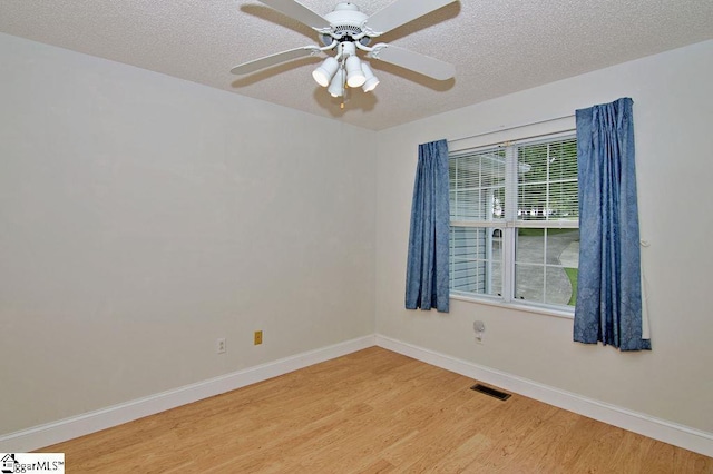 spare room with a ceiling fan, a textured ceiling, visible vents, baseboards, and light wood-style flooring
