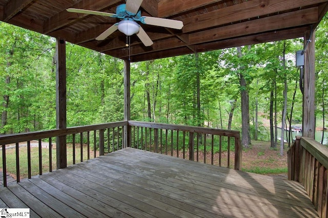 deck featuring a view of trees and ceiling fan