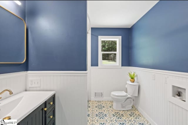 bathroom with vanity, wainscoting, toilet, and visible vents