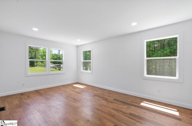 empty room with recessed lighting, baseboards, and hardwood / wood-style flooring