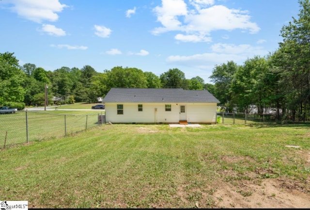 rear view of house with a fenced backyard and a yard