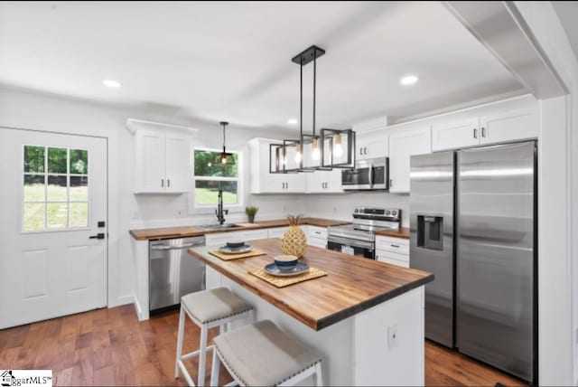 kitchen with plenty of natural light, a sink, appliances with stainless steel finishes, and butcher block counters