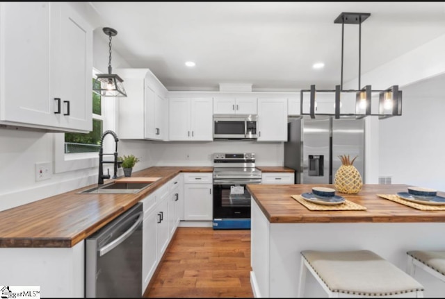 kitchen featuring a sink, light wood finished floors, butcher block countertops, stainless steel appliances, and white cabinetry