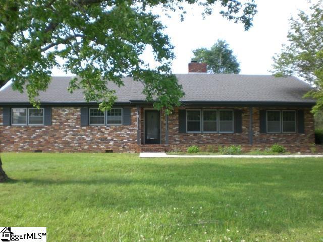 ranch-style home with brick siding, a shingled roof, a front lawn, and a chimney