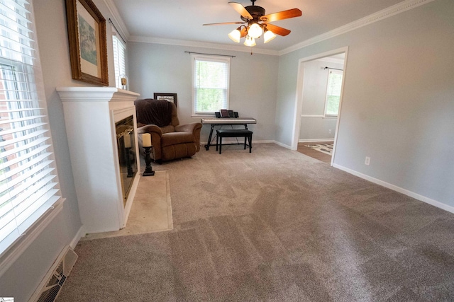 living area with ceiling fan, light carpet, a fireplace, baseboards, and ornamental molding