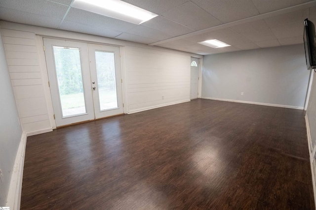 unfurnished room with baseboards, a drop ceiling, dark wood-style floors, and french doors